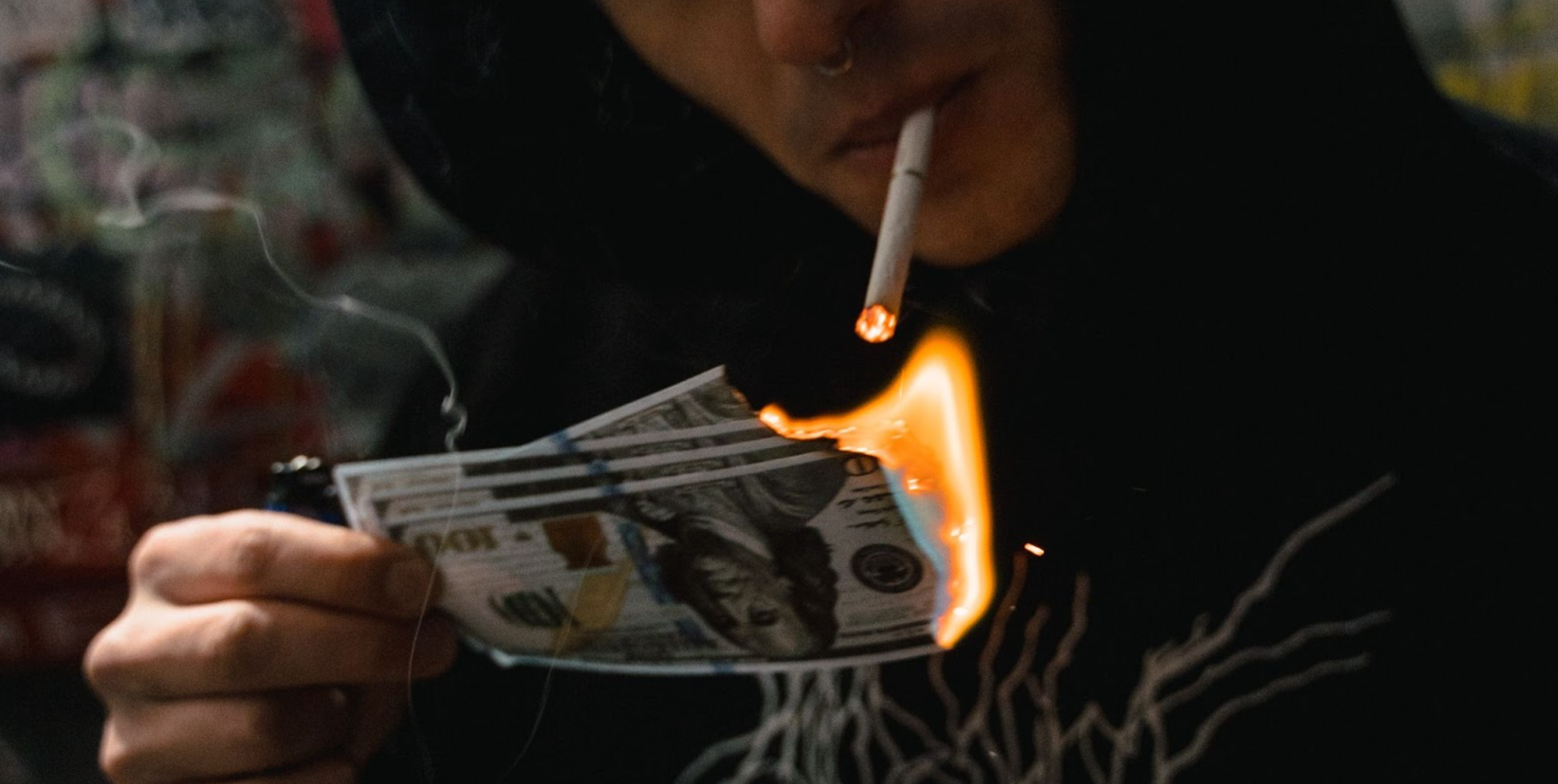 Someone smoking lighting a cigarette with burning money